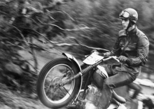 Old black and white picture of man riding a motorcycle