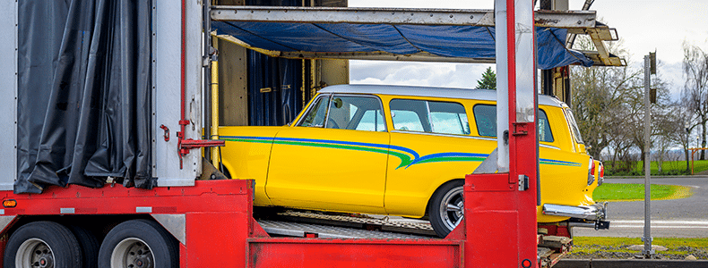Yellow classic car being loaded onto trailer for interstate shipping